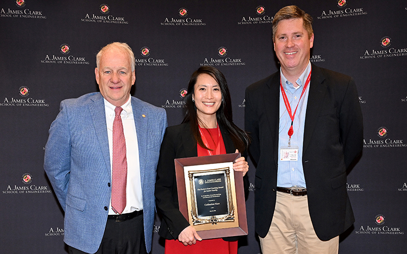 Catherine Kuo stands between the award presenters holding her award plaque