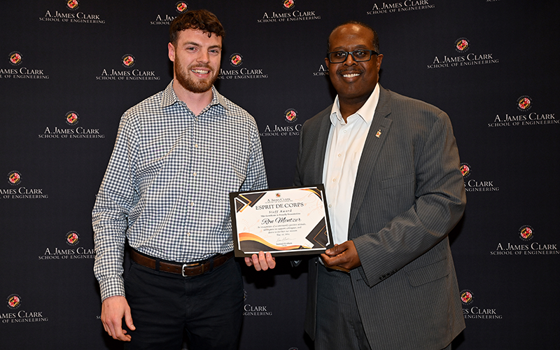 Ron Mentzer stands with Dean Graham in front of a Maryland Engineering backdrop while they both hold an end of his award certificate