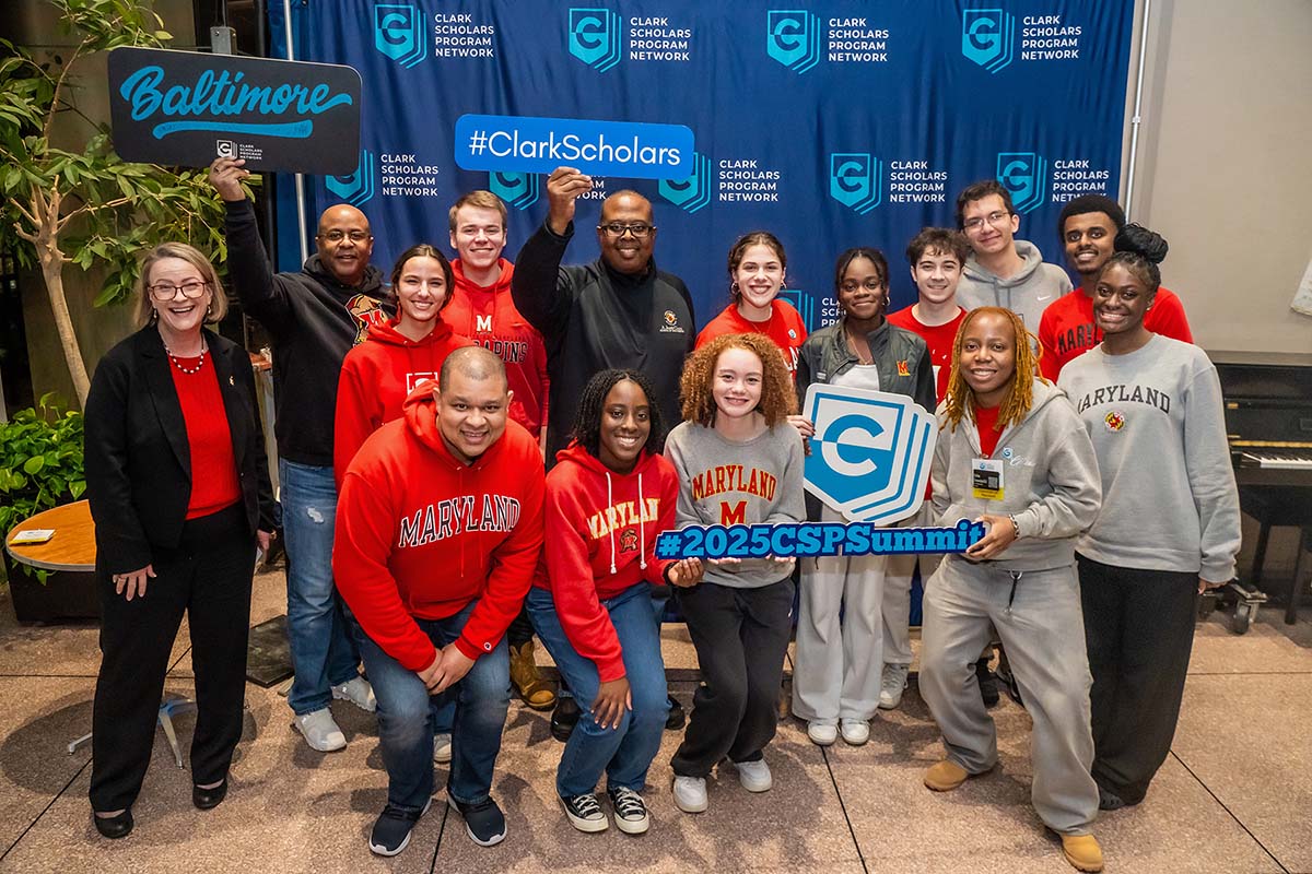 Dean Graham holds a #ClarkScholars sign and poses with students