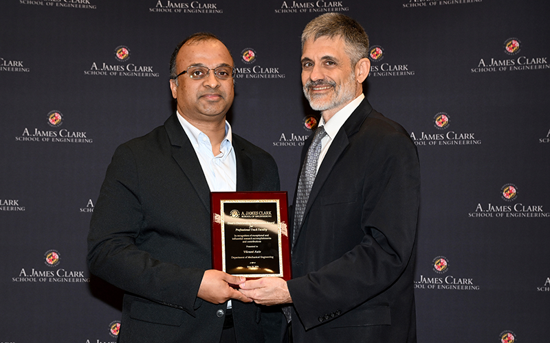 Vikrant Aute stands with Hugh Bruck in front of a Maryland Engineering backdrop holding their award plaque