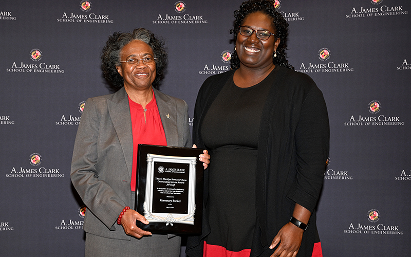 Rosemary Parker stands next to Akua Asa-Awuku holding their award plaque in front of a Maryland Engineering backdrop