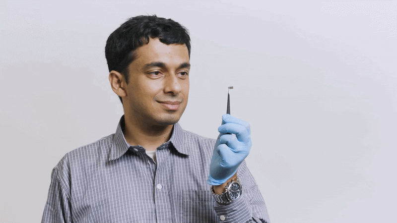 Avik Dutt wears protective equipment and examines a computer chip