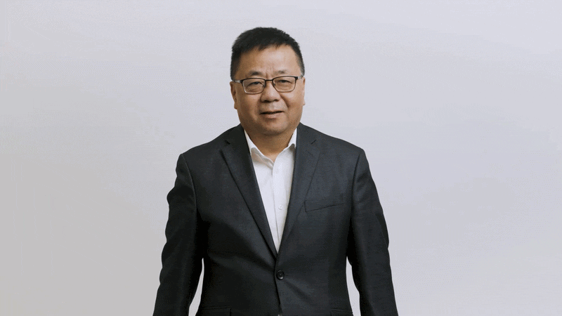 Chunsheng Wang holds up a battery pack with his arms crossed