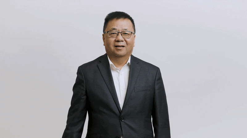 Chunsheng Wang holds up a battery pack with his arms crossed