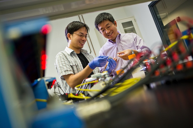 Professors Liangbing Hu and Teng Li holding a modified lithium-metal battery with a wooden negative electrode