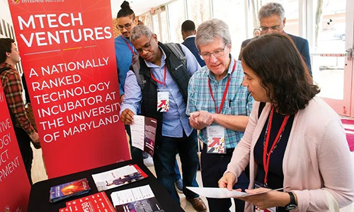 three visitors look at materials at an information table at an Mtech event