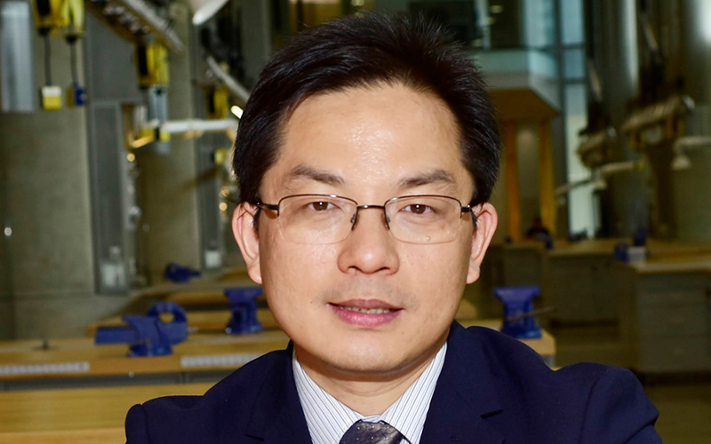 Professor Liangbing Hu poses for headshot in blue suit and glasses