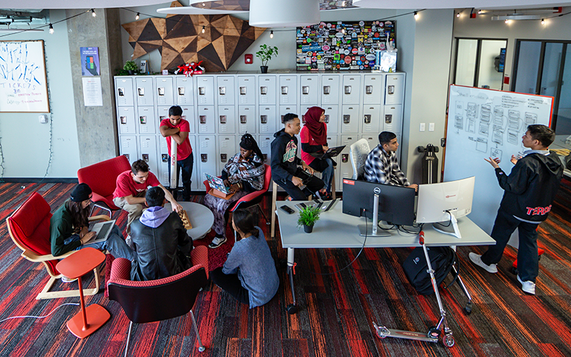 students sit around a table and whiteboard in the Startup Shell while working together on a project.