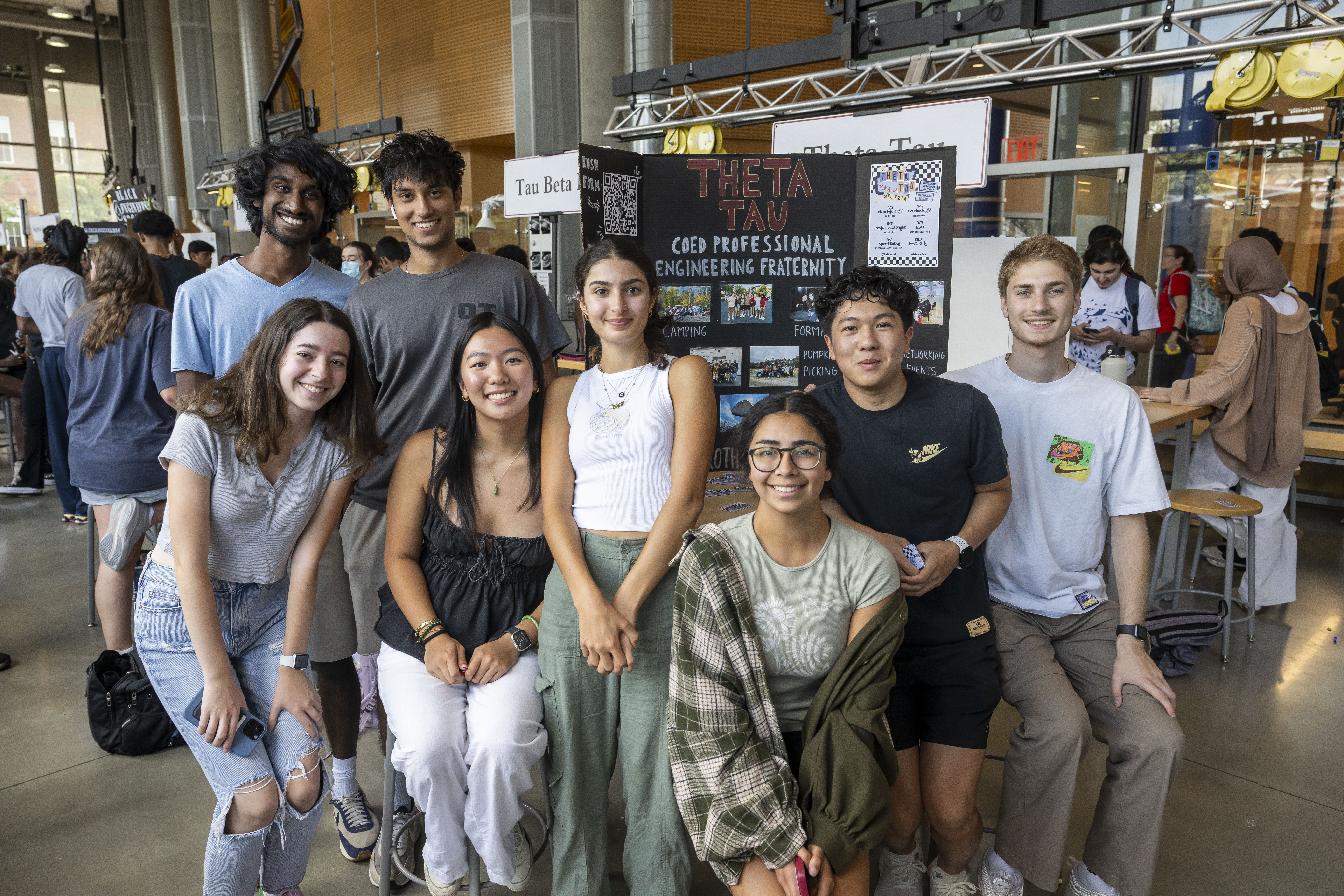 Students posing in front of poster at the student organization fair