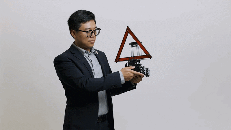Terry Yang examines a small autonomous vehicle that has a large reflective triangle