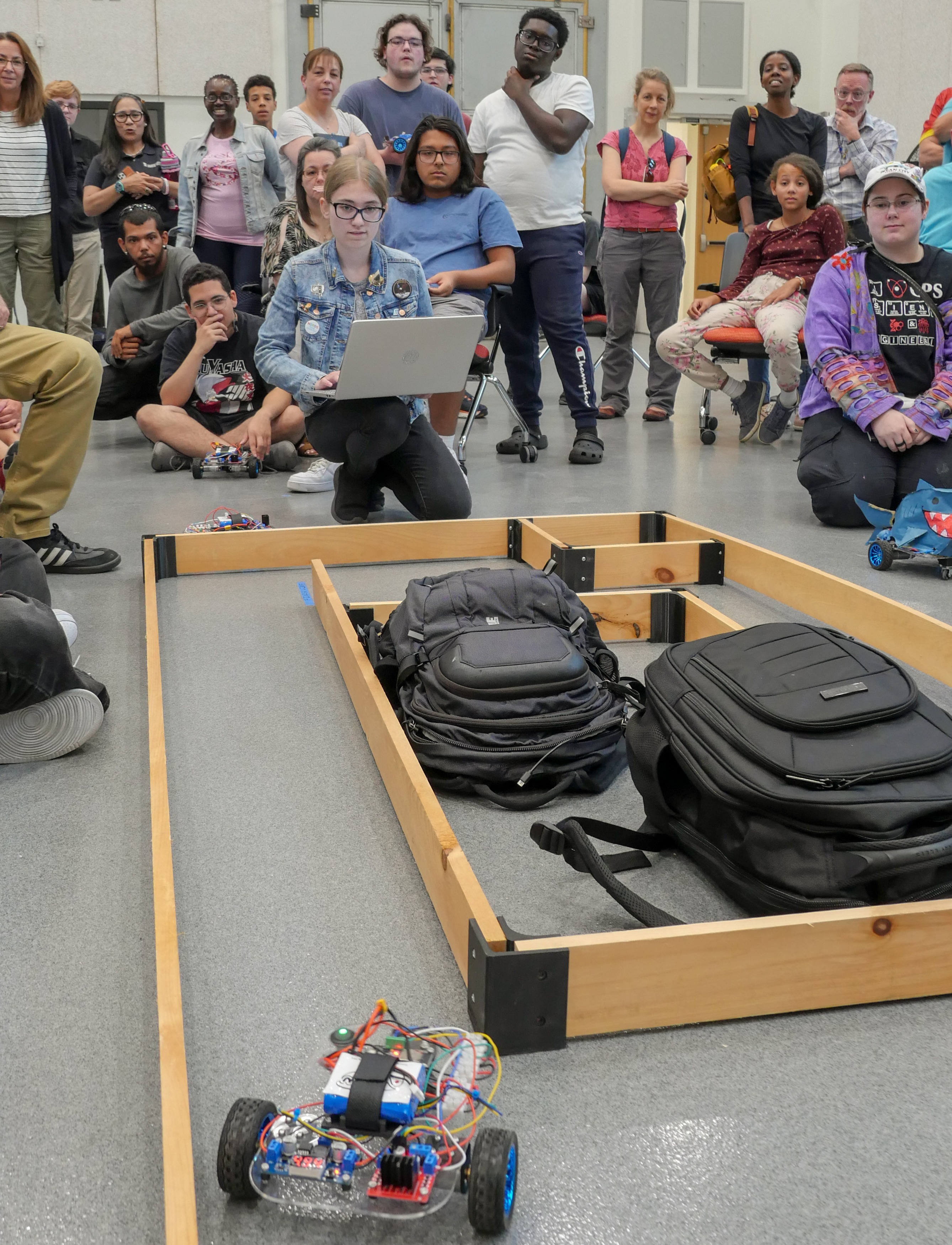 Student remotely guides a robot through a maze and others watch intently