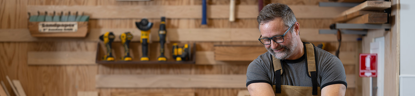 Man in coveralls cuts wood with a table saw