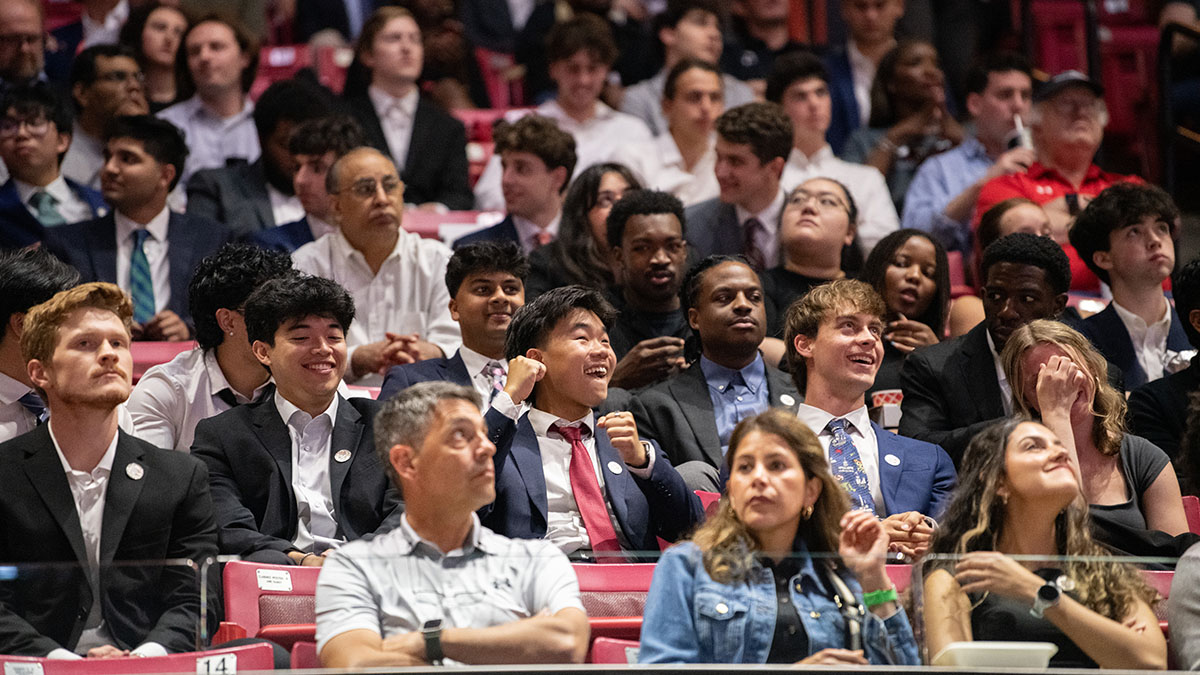 A packed crowd with a student raising his fist in the air with excitement