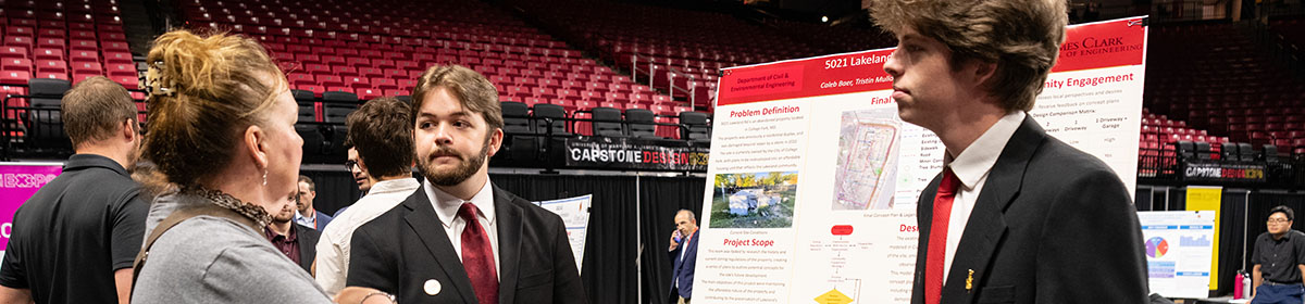 Two civil and environmental engineering students listen as an attendee asks a question about their research