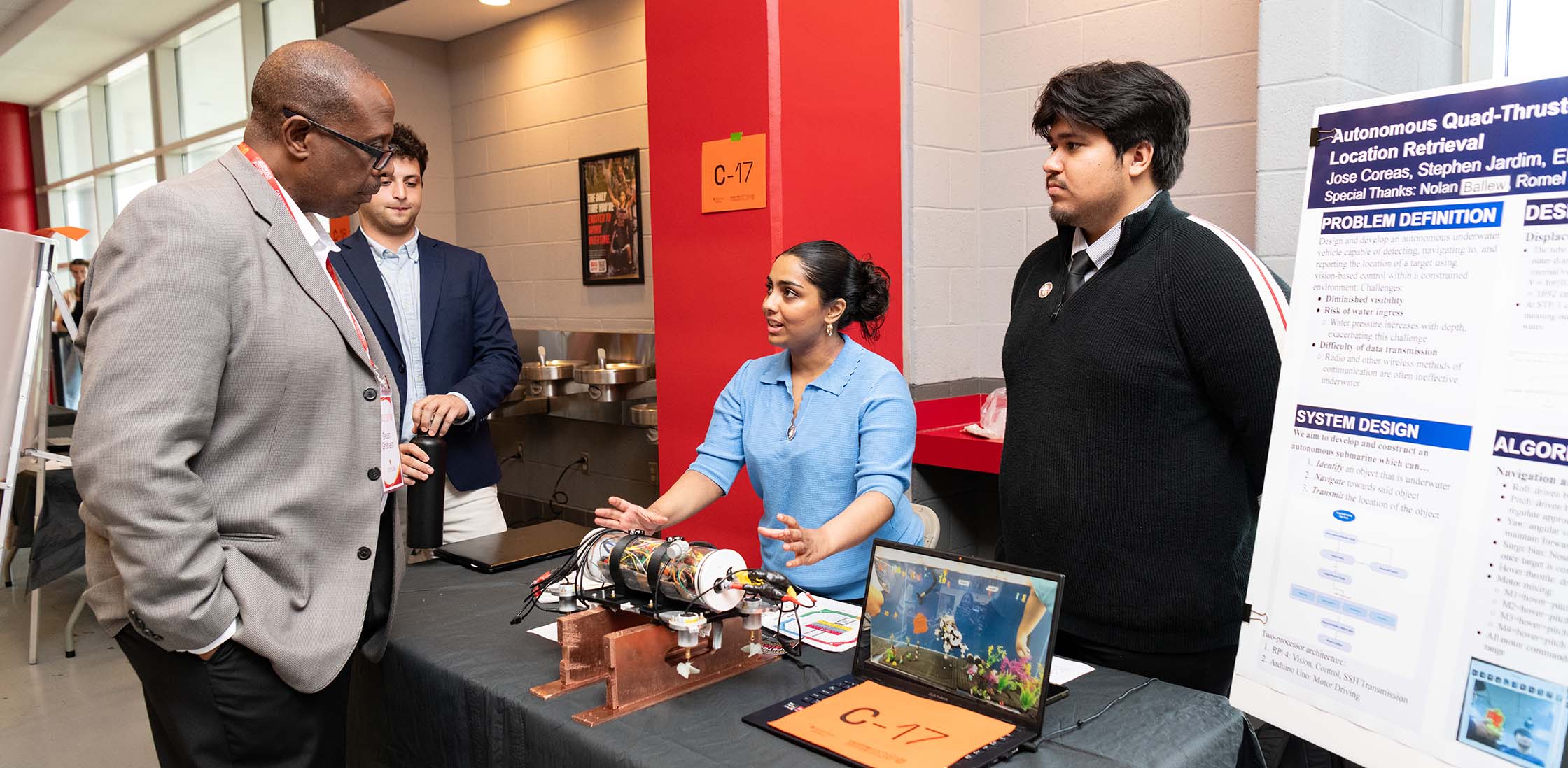 Two students explain their research project to Dean Graham