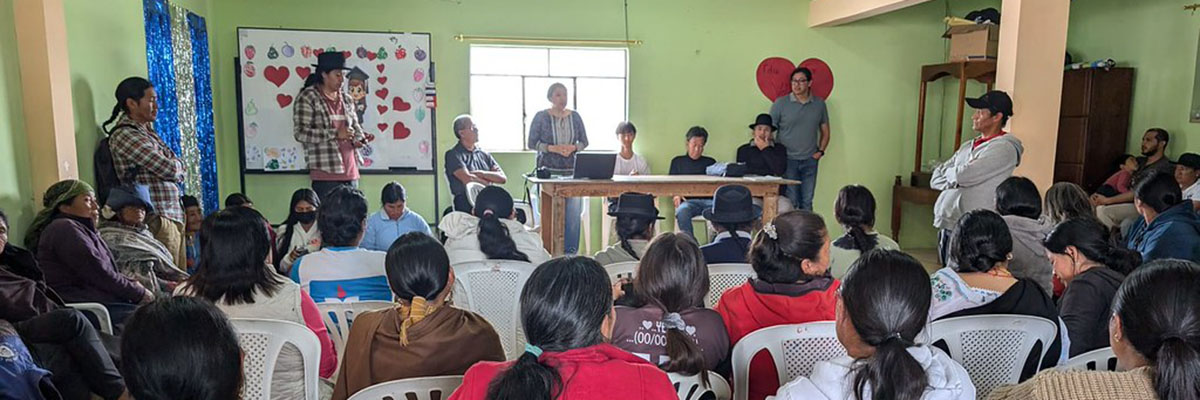 Five people—including three students—sit behind a table, presenting to a packed room of attendees