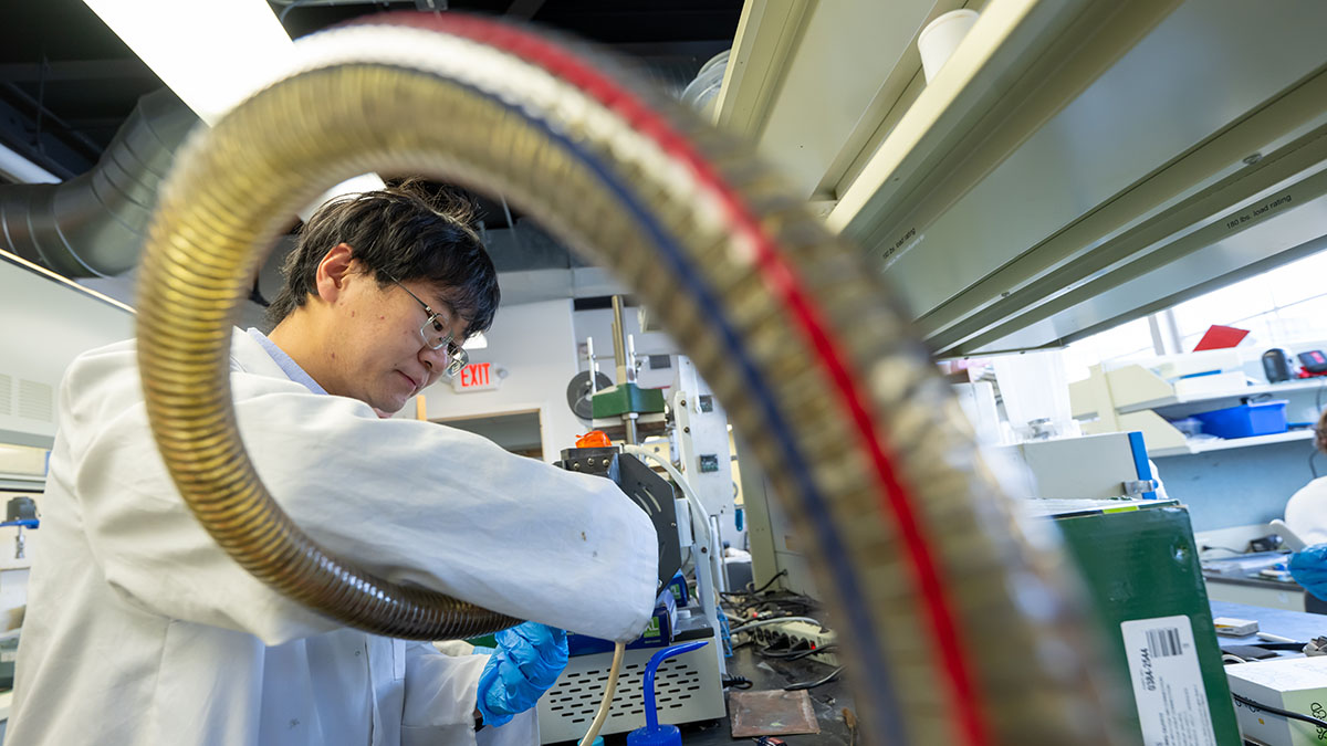 Student in an extreme materials lab with a tube framing his face