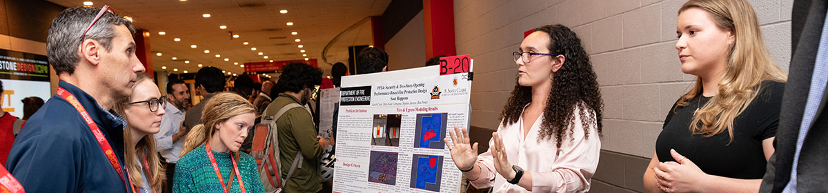 Two fire protection engineering students explain their research to three attendees