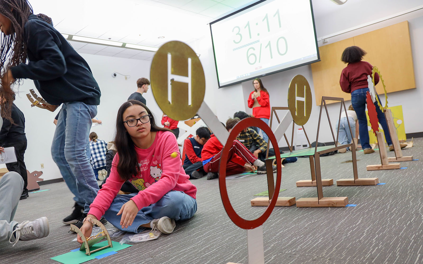 A student sits on the floor playing with an engineering kit