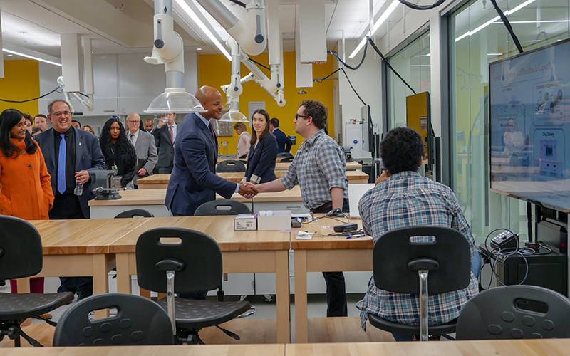 Governor Wes Moore shakes the hand of a researcher