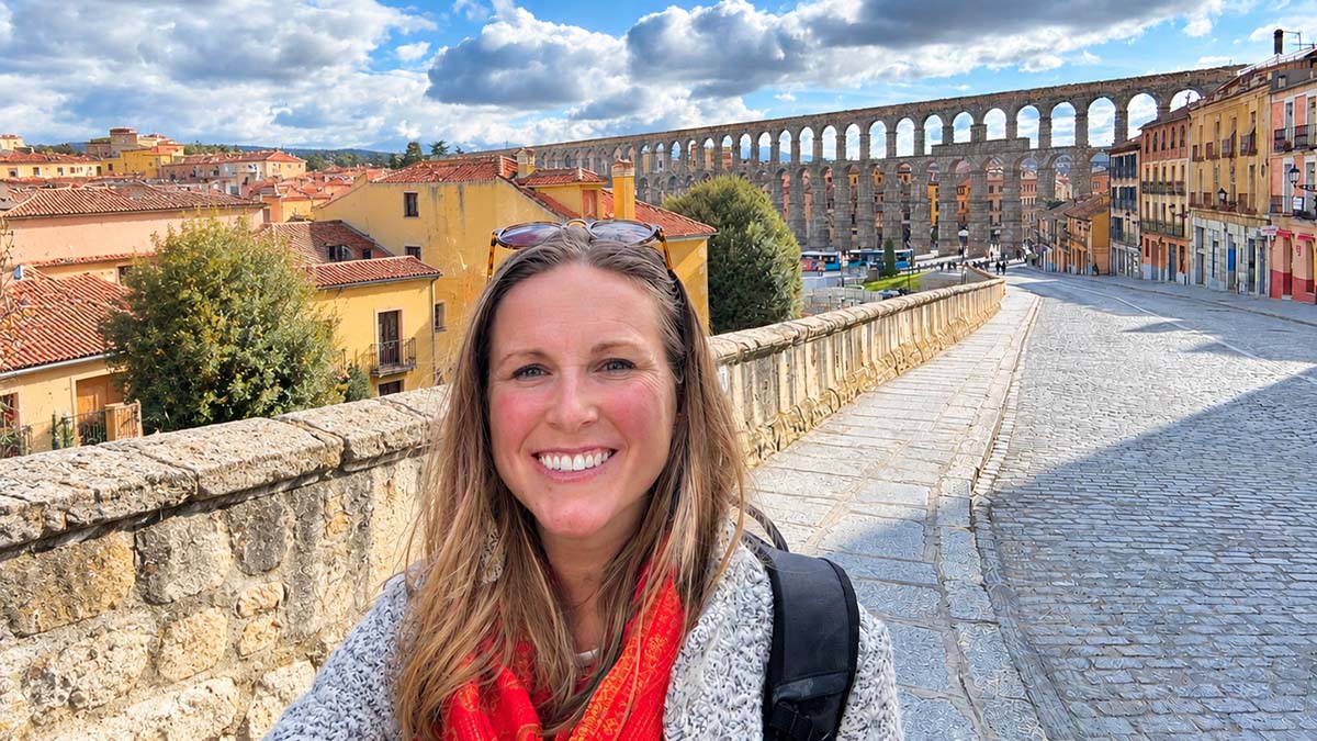 A person posing in front of an aqueduct in Spain