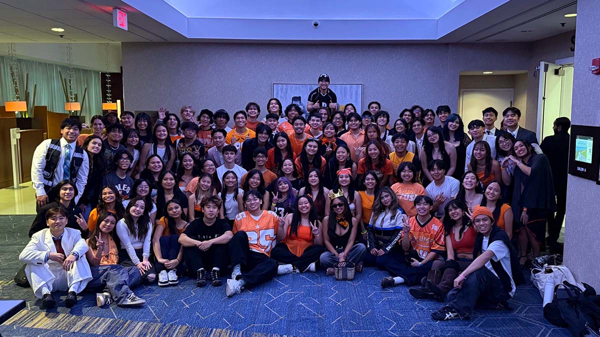 Dozens of students pose in a darkened room