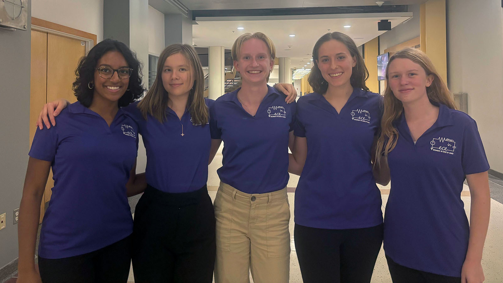 Natalie Venginickal poses with four other women, each wearing a purple ECE shirt