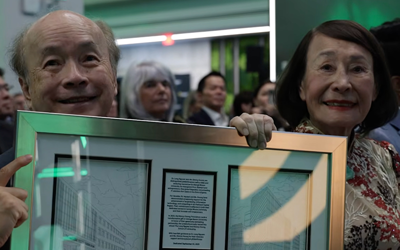 Kimmy Duong and Long Nguyen hold a framed plaque.