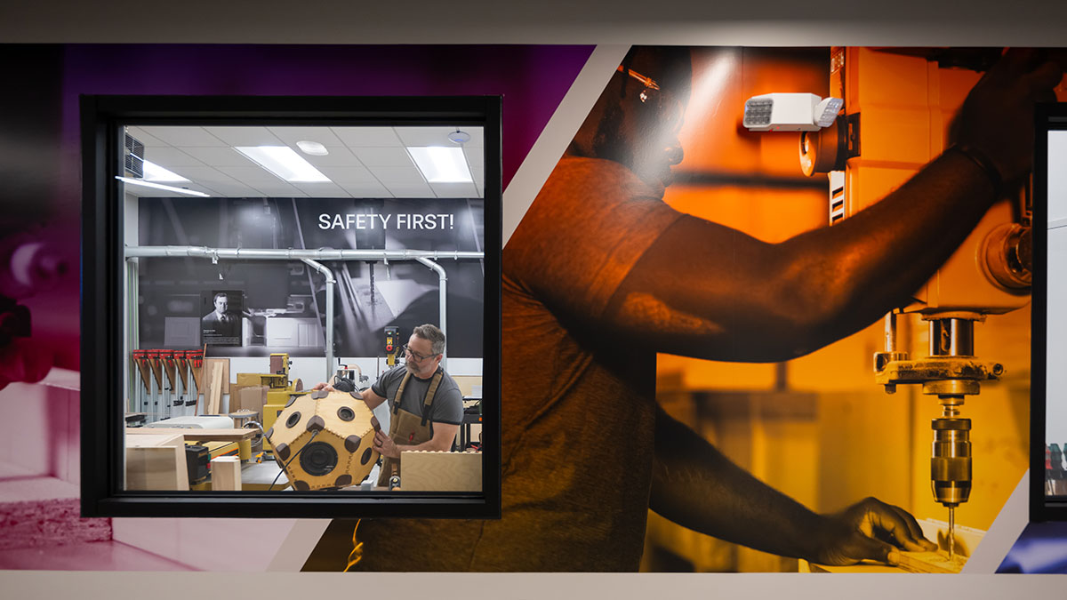 Looking through a hallway window at a man in a makerspace