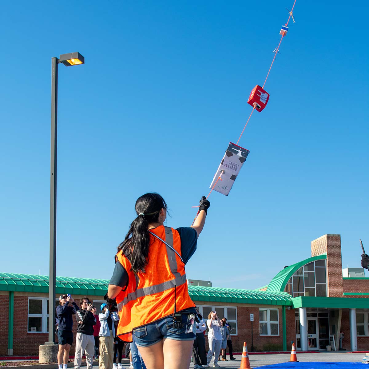 Student holds a balloon payload line that's lifting into the sky