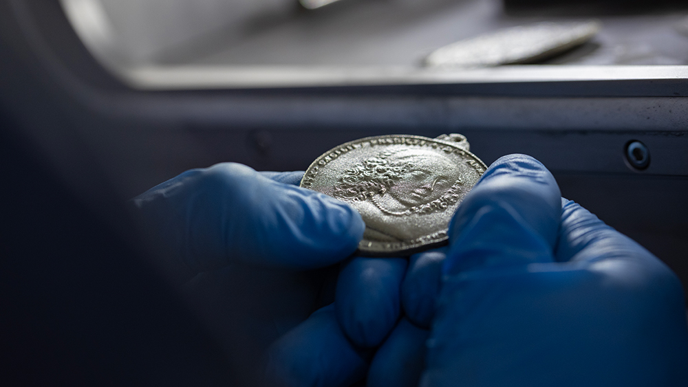 Gloved hand holds a 3D-printed Piscataway Peace Medal