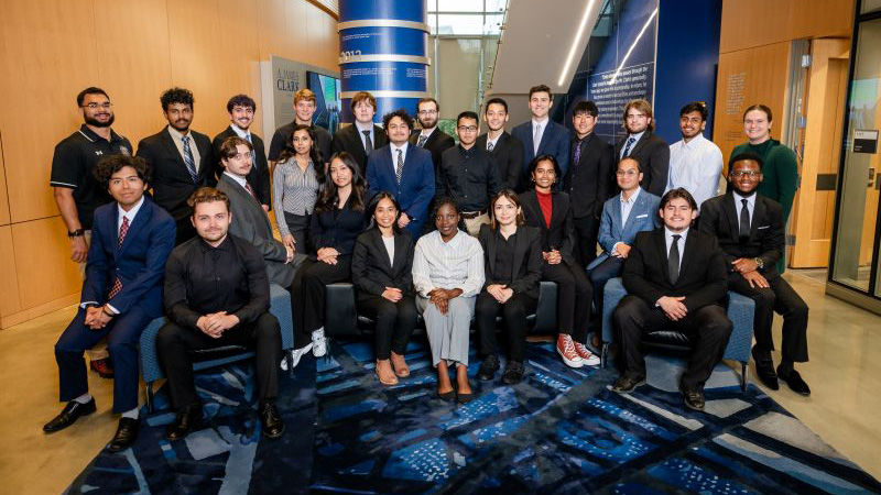 A large group of students dressed in suits poses