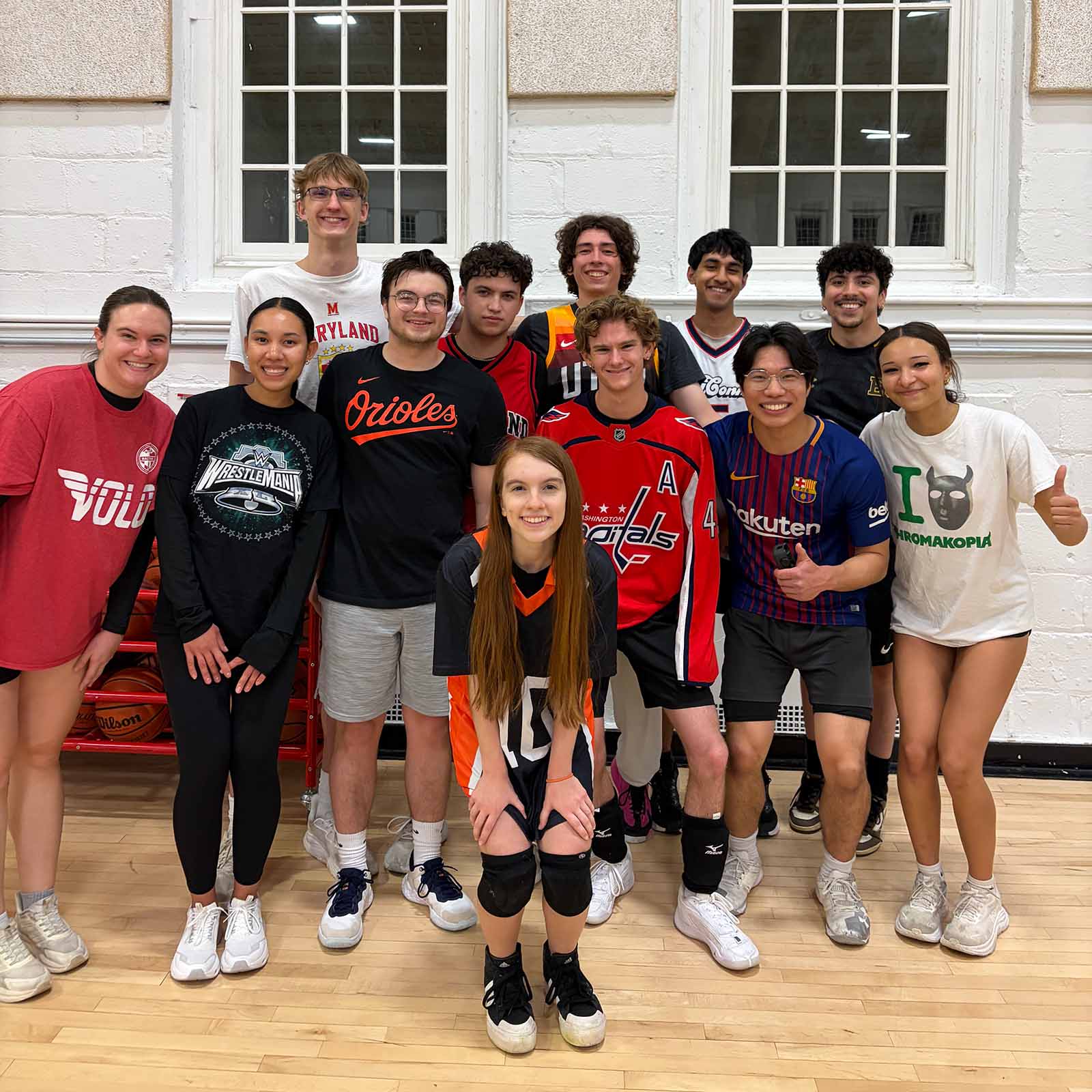 A group of students in athletic clothes poses in a gym