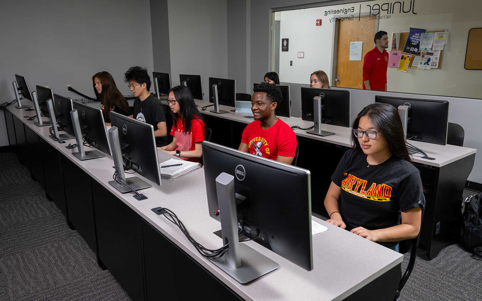 Students sit before monitors in a lab