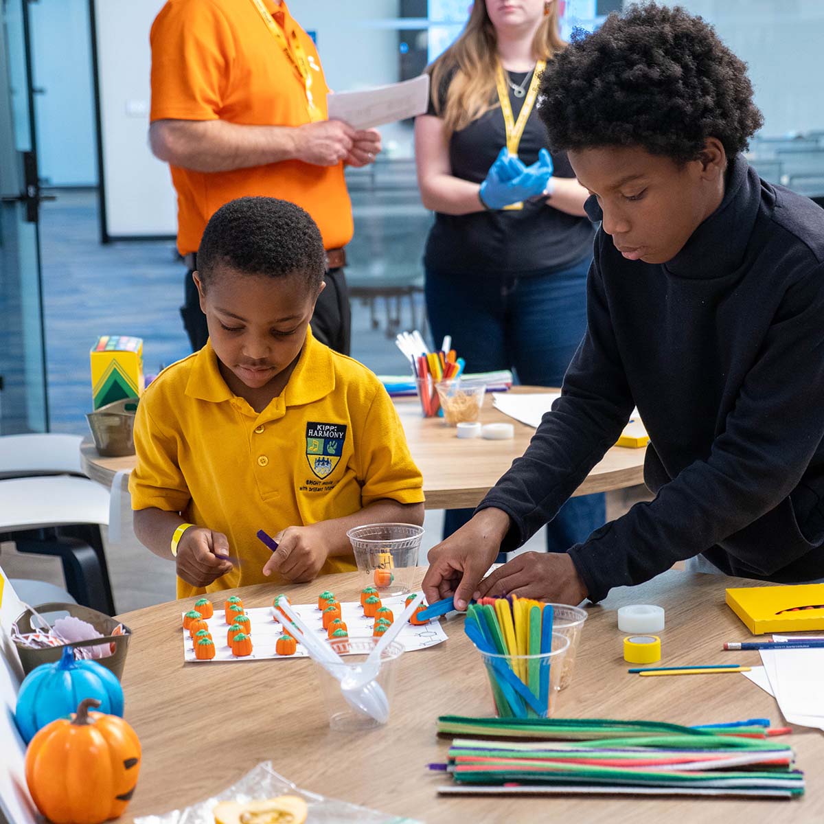 A youth helps a younger child with a craft project