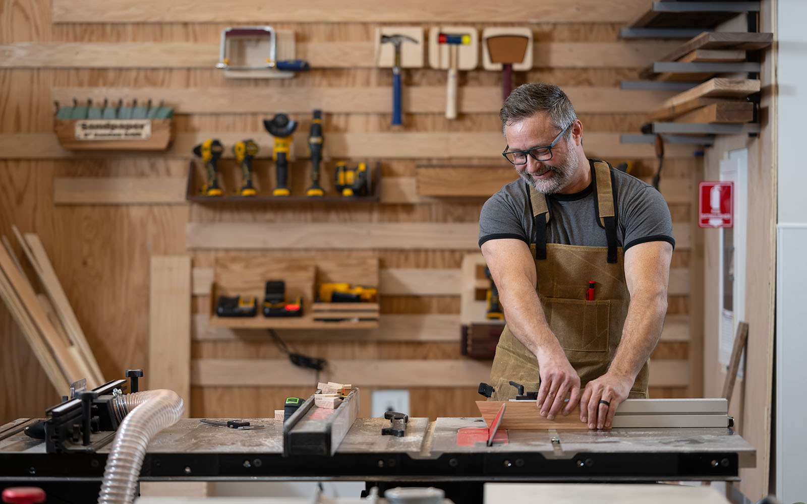 Man in coveralls cuts wood with a table saw