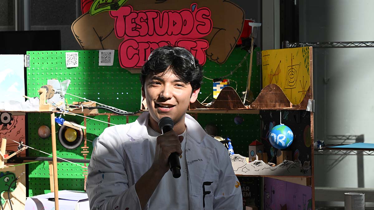 A student holds a microphone to describe the Testudo's Circuit device